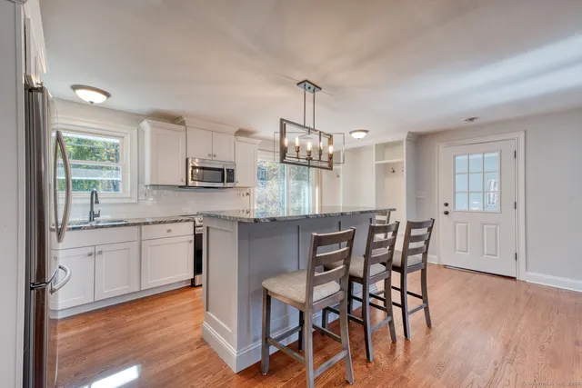a kitchen with stainless steel appliances granite countertop a kitchen island hardwood floor and a sink