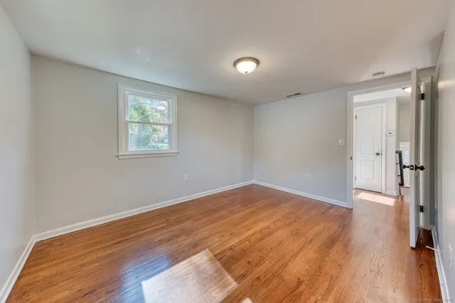 an empty room with wooden floor and a window