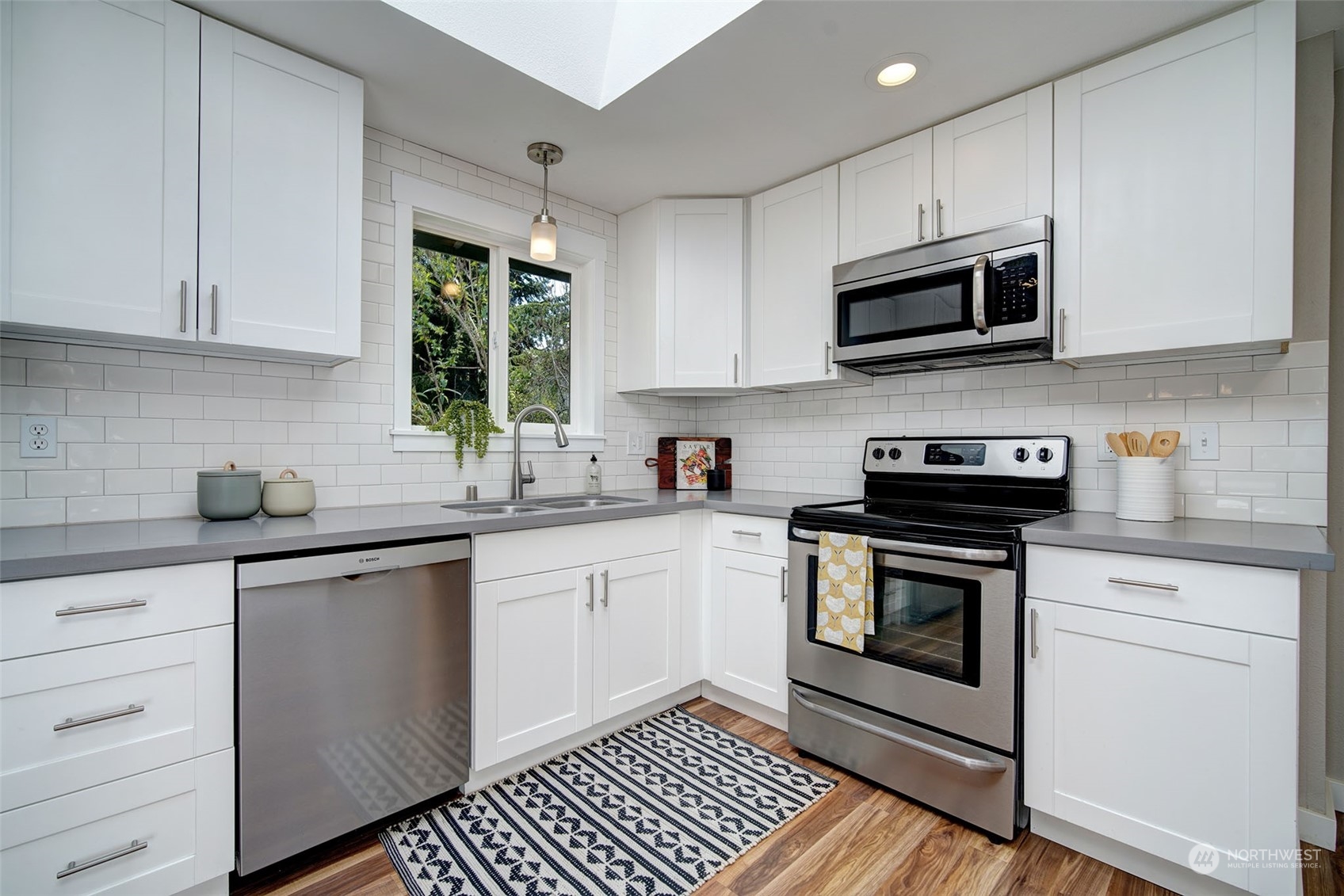 9504 233rd Street Southwest Edmonds, WA 98020 - Photo 8 of 26 a kitchen with stainless steel appliances granite countertop white cabinets a sink a stove a microwave and wooden cabinets