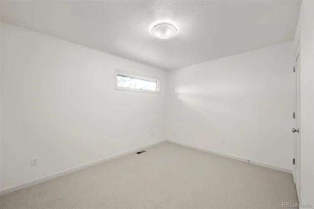 an empty room with windows and fireplace