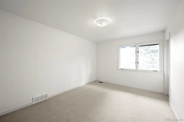 an empty room with fireplace and a ceiling fan