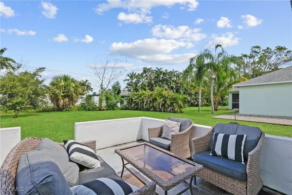a view of a patio with couches chairs under an umbrella