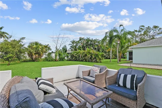 a view of a patio with couches chairs under an umbrella