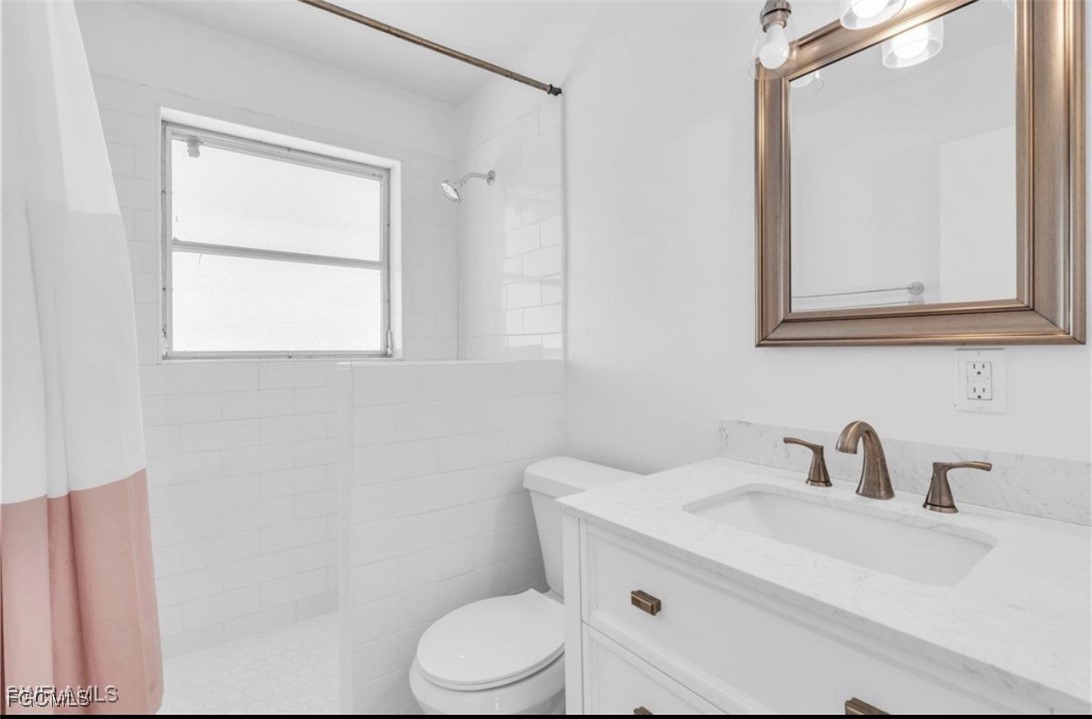 1661 Coronado Road Fort Myers, FL 33901 - Photo 44 of 50 a bathroom with a toilet a sink a mirror and a window