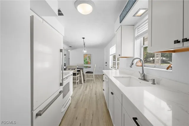 a kitchen with counter top space a sink wooden floor and stainless steel appliances