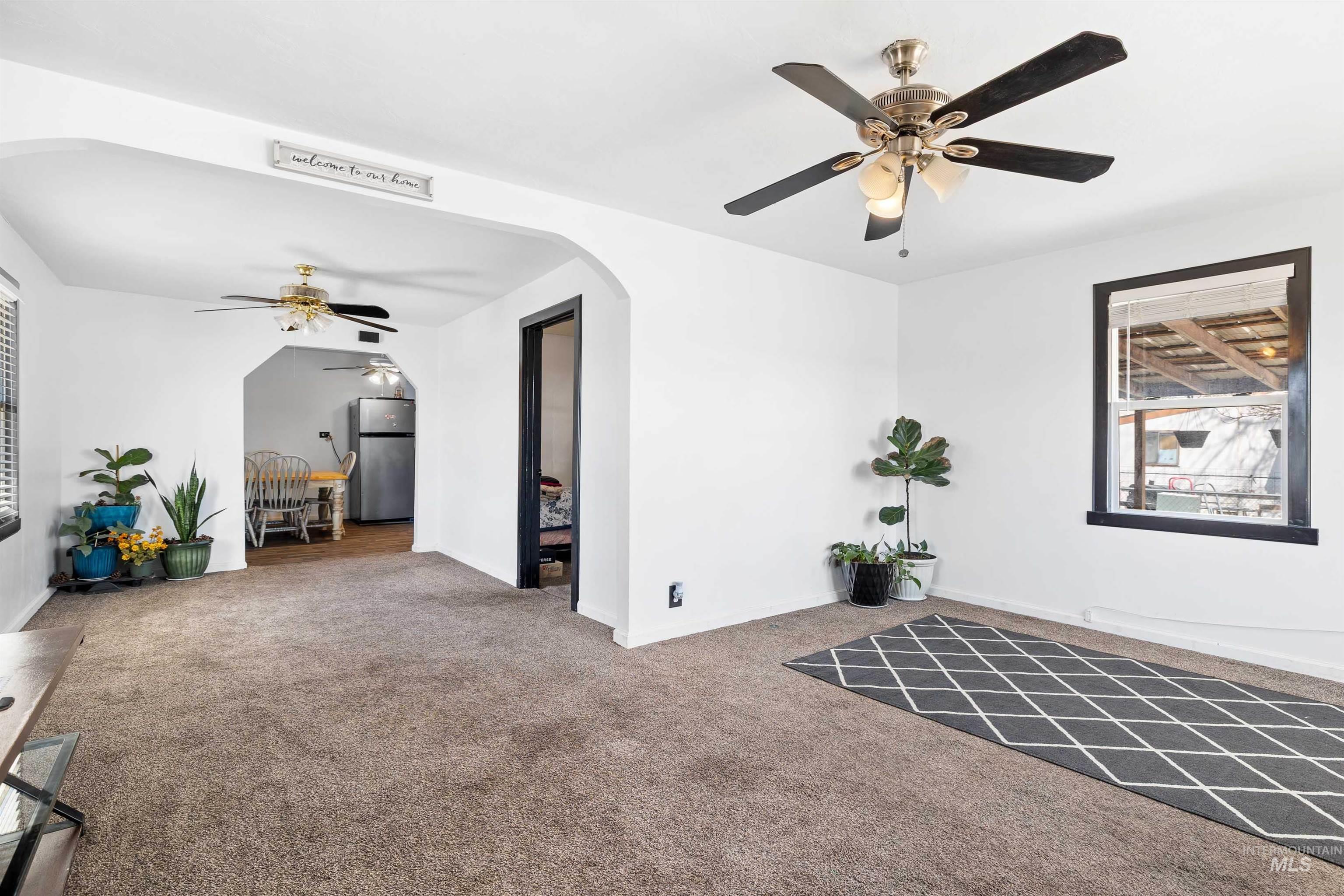 102 East 6th Street Rupert, ID 83350 - Photo 5 of 27 Carpeted room with white walls, dark window trim, and a ceiling fan