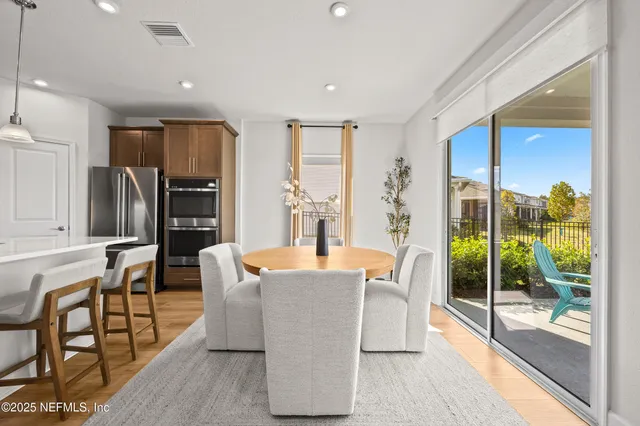 a dining room with furniture a floor to ceiling window and wooden floor