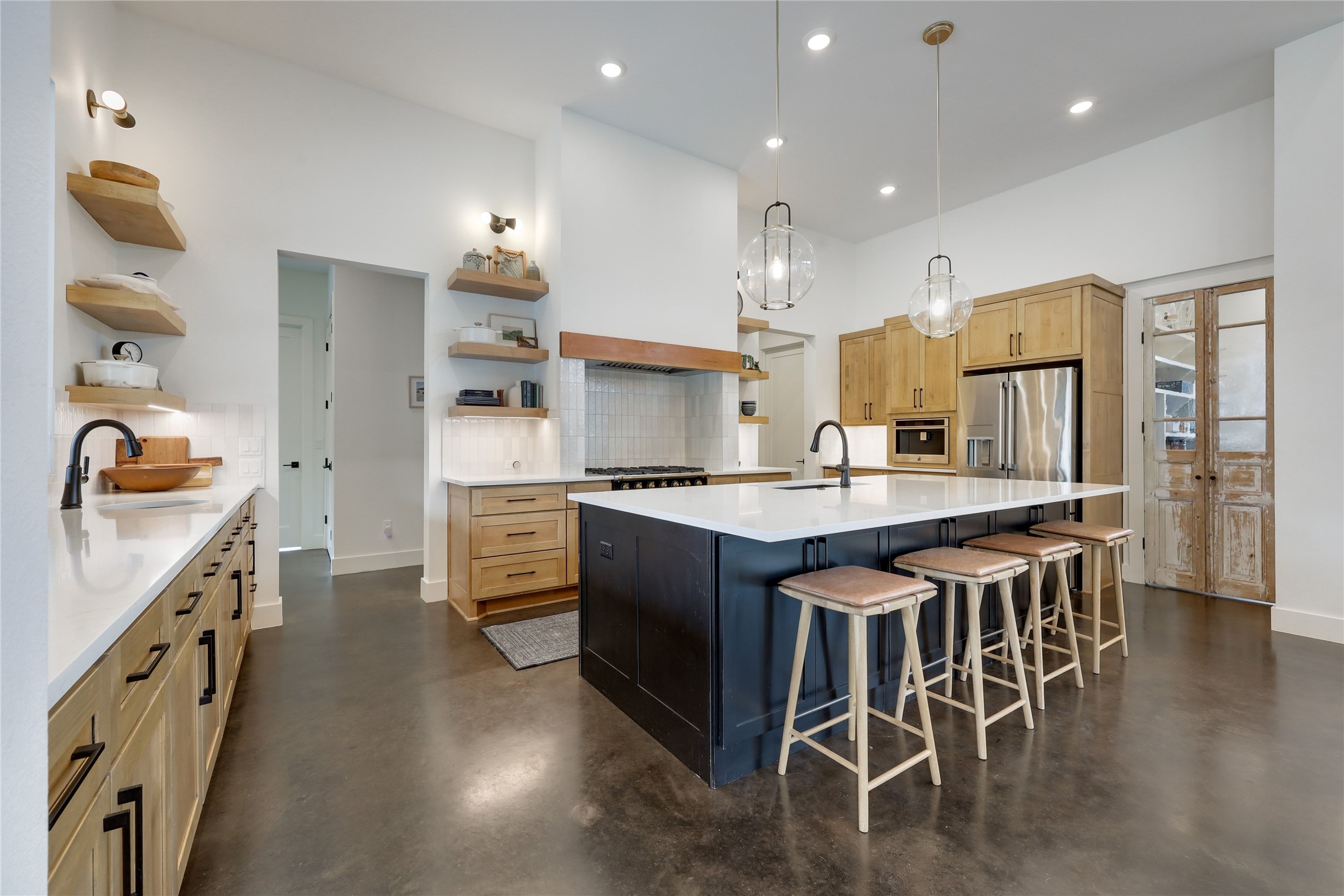 329 Calvary Cove Dripping Springs, TX 78620 - Photo 6 of 40 a kitchen with stainless steel appliances granite countertop a stove top oven a sink a refrigerator and white cabinets with wooden floor