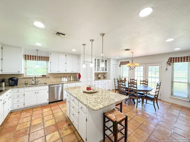 a kitchen with a stove a sink dishwasher and a dining table with cabinets