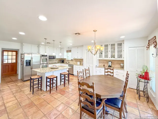 a dining room with stainless steel appliances kitchen island granite countertop a dining table chairs and view living room