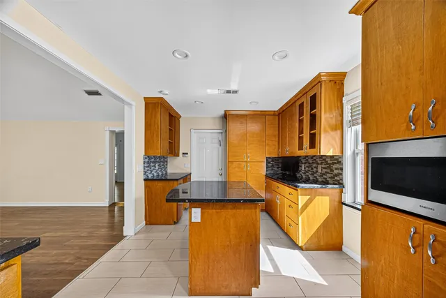 a view of kitchen with kitchen island granite countertop cabinets and flat screen tv