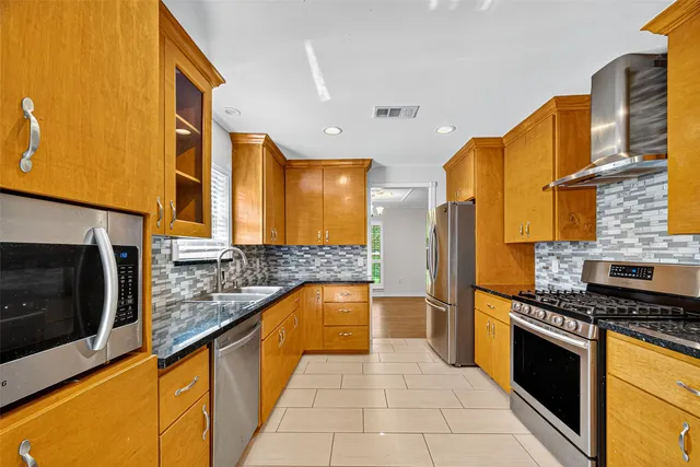 a kitchen with stainless steel appliances granite countertop a stove a sink and a microwave