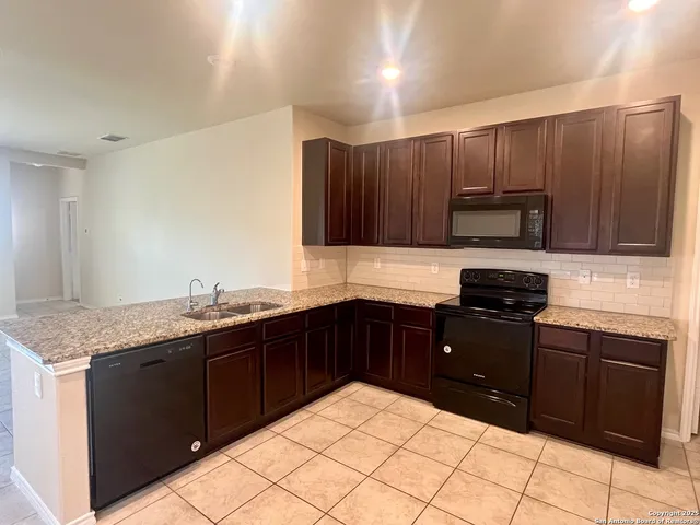 a kitchen with granite countertop wooden cabinets and black stainless steel appliances
