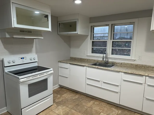 a kitchen with granite countertop white cabinets and window