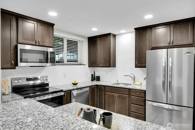 a kitchen with stainless steel appliances a refrigerator sink and microwave