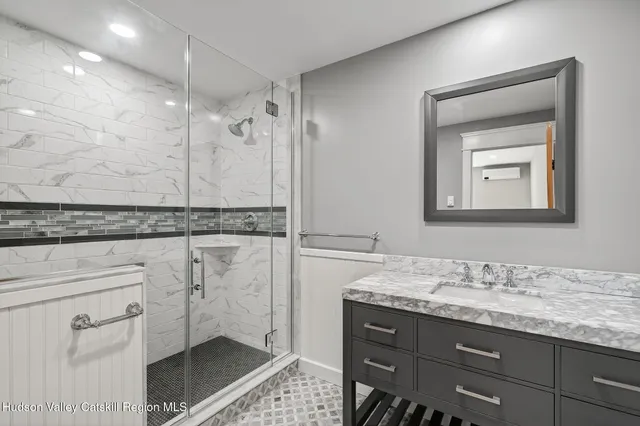 a bathroom with a granite countertop sink a mirror and a shower