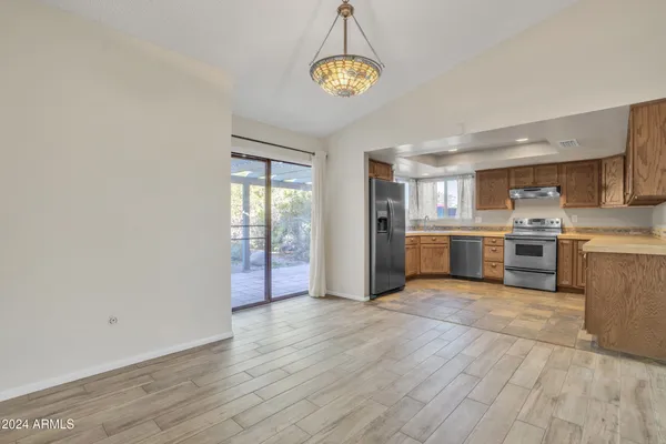 a large kitchen with stainless steel appliances granite countertop a stove top oven a sink dishwasher and a refrigerator