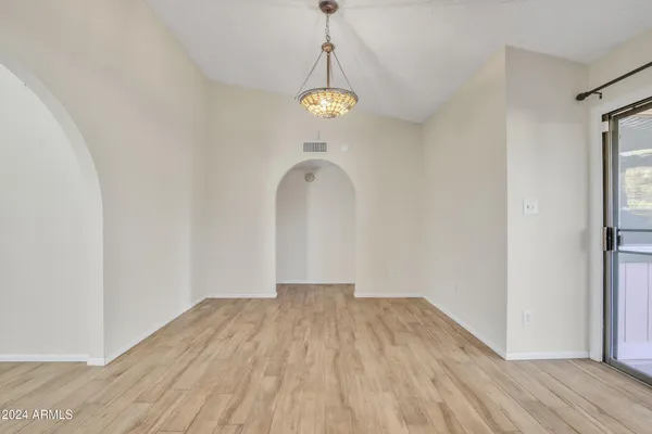 an empty room with wooden floor and fan