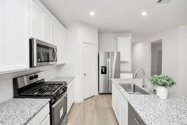 a kitchen with stainless steel appliances granite countertop a sink stove and refrigerator