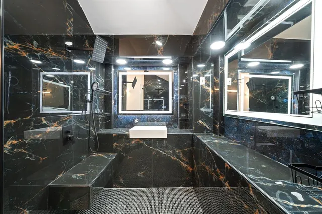 a bathroom with a large mirror vanity and a shower