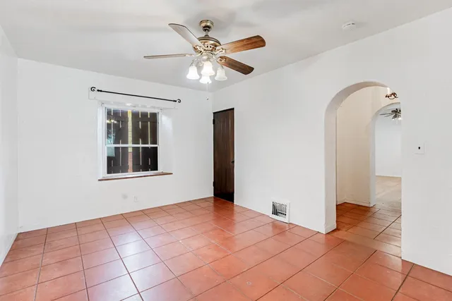 a view of an empty room with window and chandelier fan