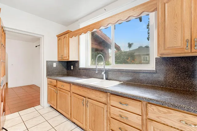 a kitchen with granite countertop a sink a window and cabinets