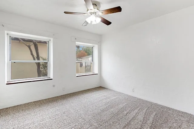 an empty room with windows and fan