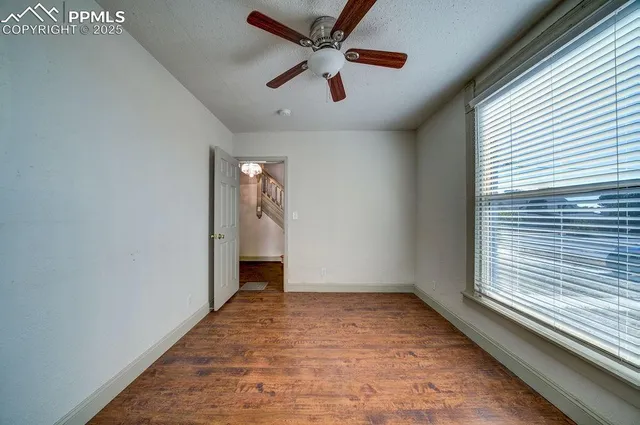 a view of empty room with wooden floor and fan
