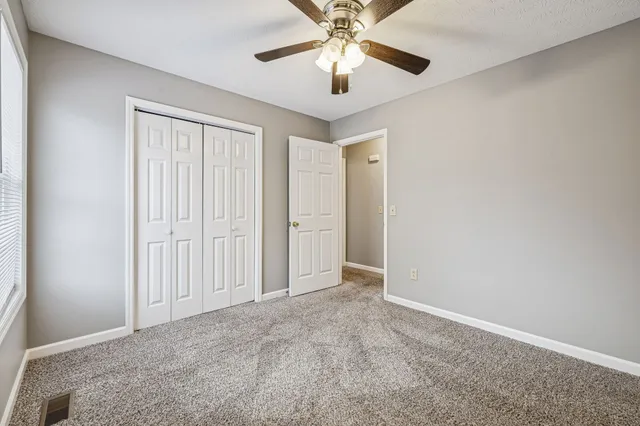 an empty room with closet and a chandelier fan