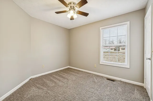 an empty room with a window and a fan