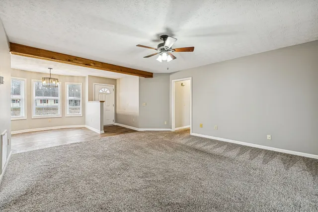 an empty room with windows and ceiling fan