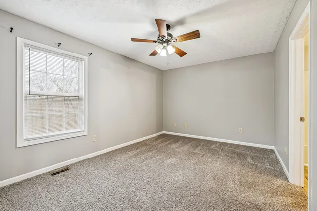 an empty room with windows and fan