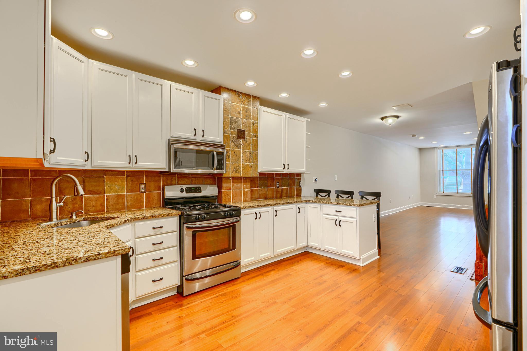 4126 Falls Road Baltimore, MD 21211 - Photo 11 of 35 a large kitchen with stainless steel appliances granite countertop a stove and a sink