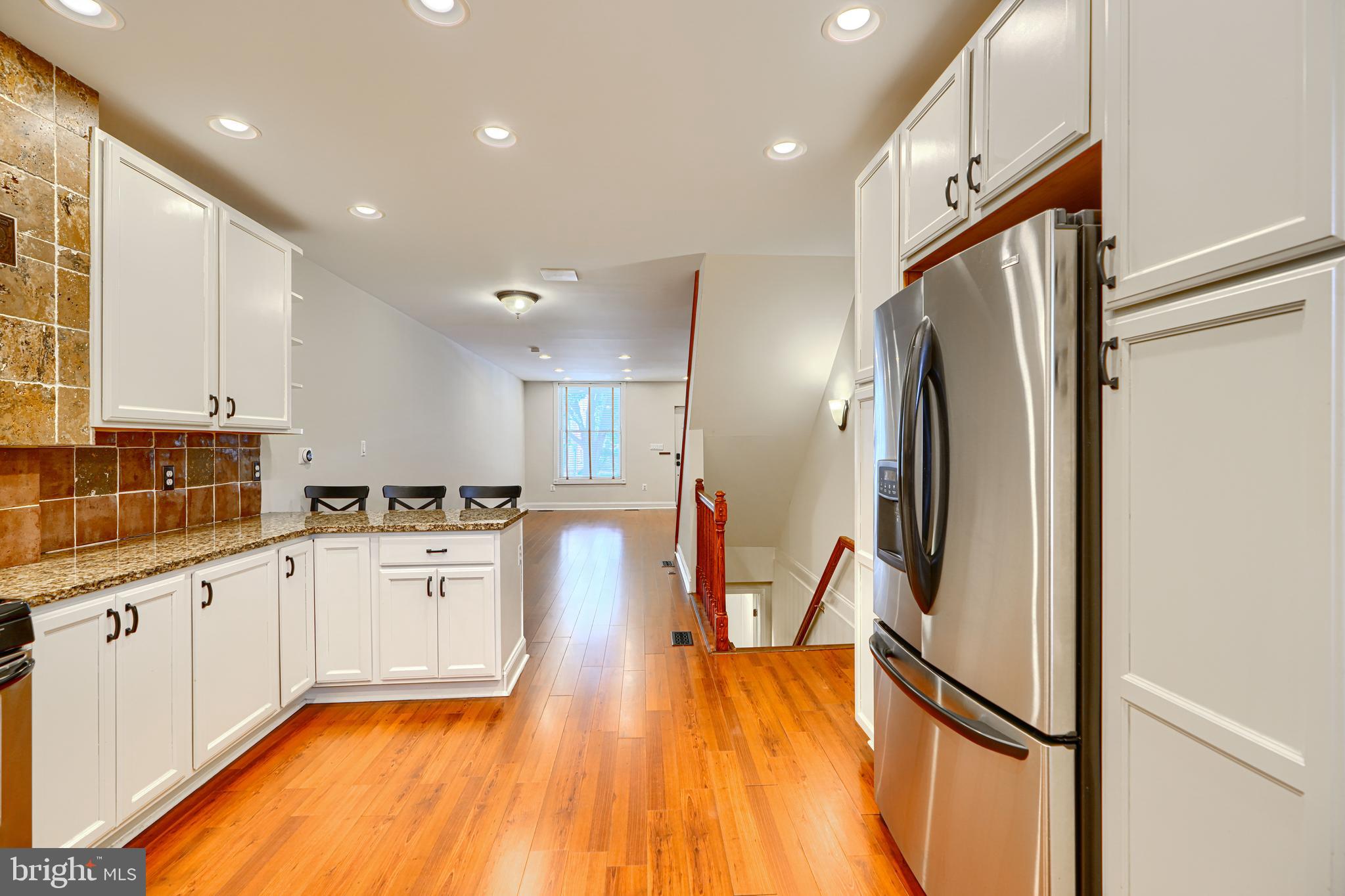 4126 Falls Road Baltimore, MD 21211 - Photo 12 of 35 a kitchen with stainless steel appliances granite countertop a refrigerator a stove and white cabinets with wooden floor
