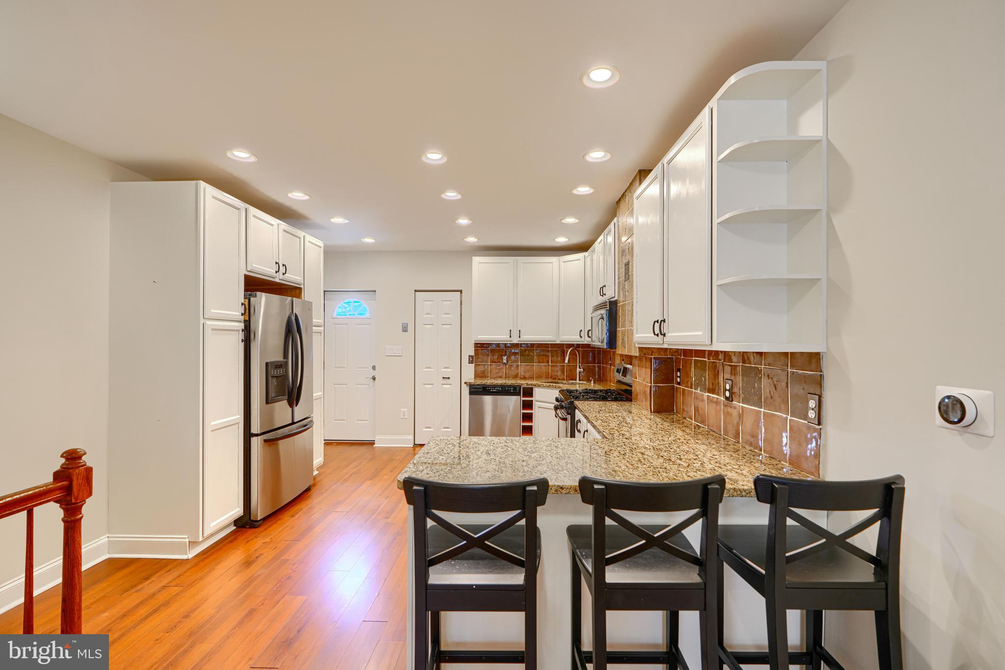 4126 Falls Road Baltimore, MD 21211 - Photo 8 of 35 a kitchen with stainless steel appliances granite countertop a dining table chairs refrigerator and microwave