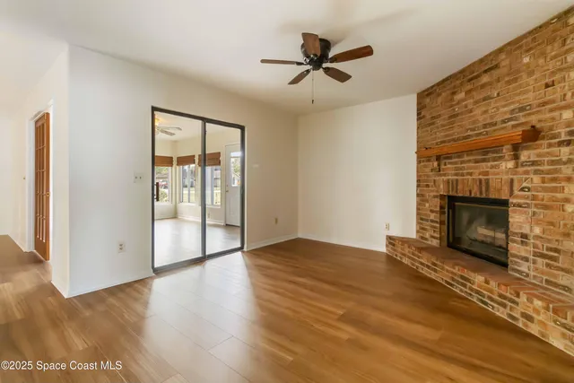 an empty room with wooden floor fireplace and windows