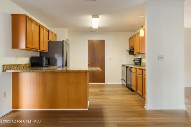 a kitchen with stainless steel appliances granite countertop a refrigerator a stove and a sink with wooden floor