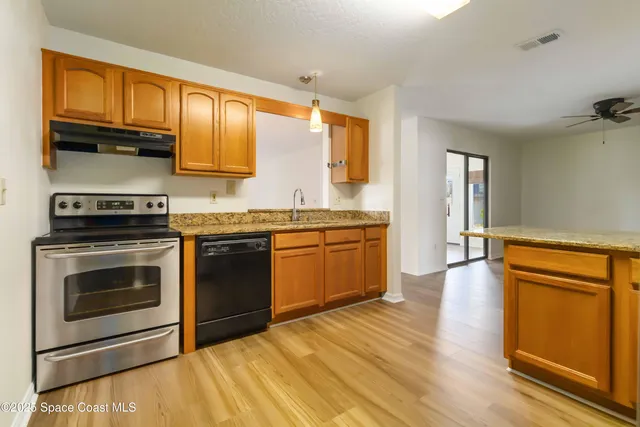 a kitchen with granite countertop wooden floors and stainless steel appliances
