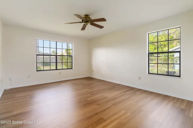 a view of an empty room with a window and wooden floor