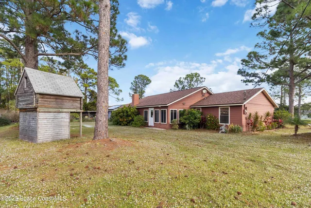 a view of a yard in front of a house with large tree