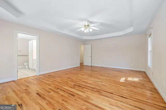 a view of empty room with wooden floor and fan