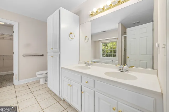 a bathroom with a granite countertop sink a toilet and a large mirror