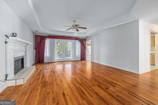 a view of an empty room with wooden floor fireplace and a window