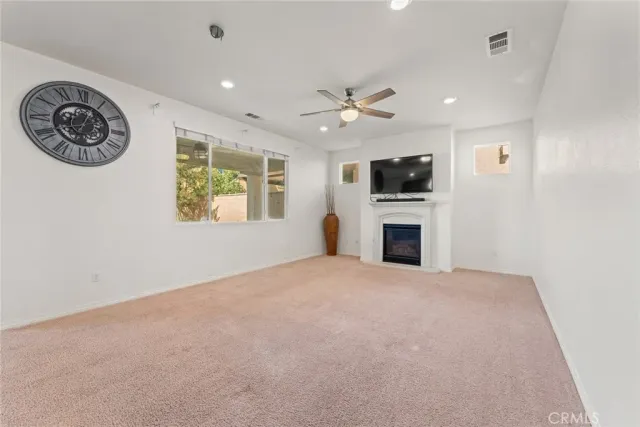 a view of a livingroom with a fireplace a window and a ceiling fan