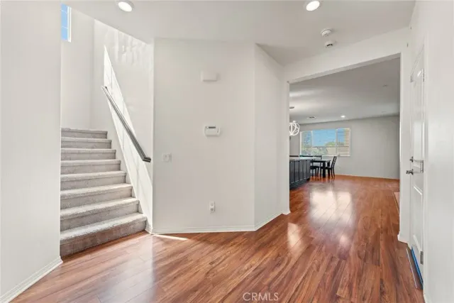 a view of a hallway with wooden floor and a bathroom