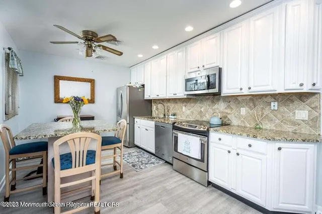 a kitchen with stainless steel appliances granite countertop a stove and white cabinets