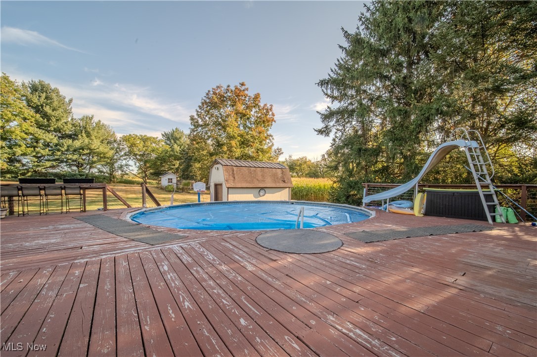 3459 Laubert Road Atwater, OH 44201 - Photo 33 of 39 View of swimming pool featuring a wooden deck, a water slide, view of scattered trees, and a shed