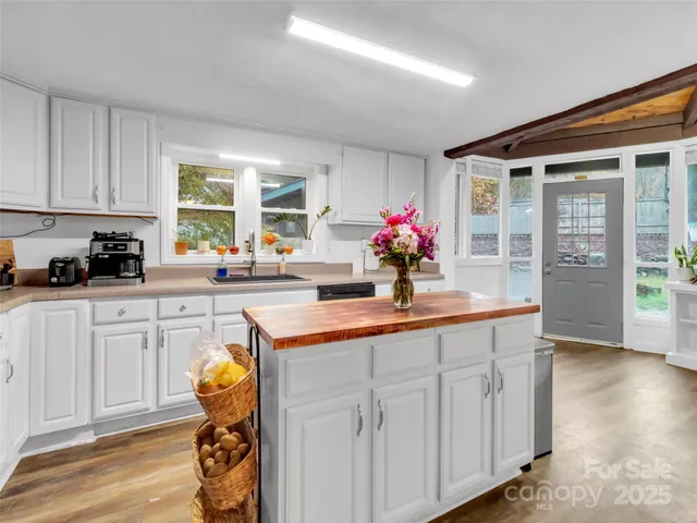 a kitchen with a white stove top oven and white cabinets with wooden floor