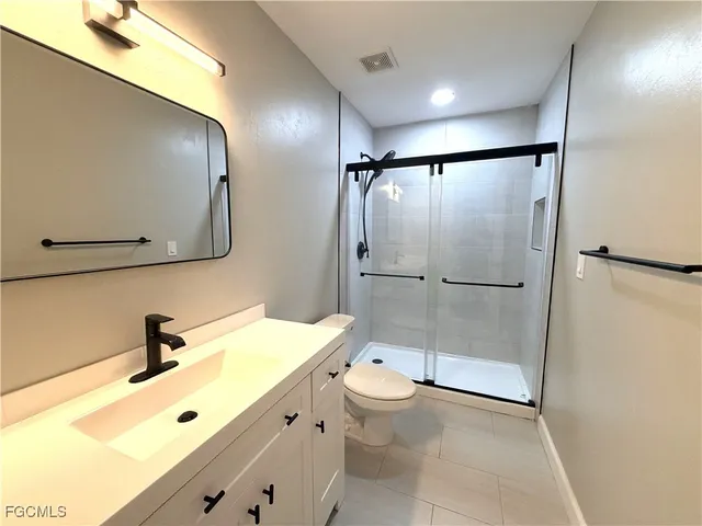 a bathroom with a double vanity sink toilet mirror and shower