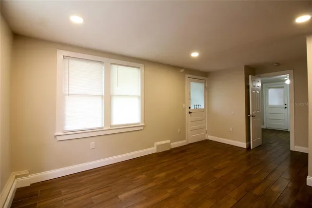 a view of an empty room with wooden floor and a window